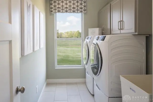 washroom with independent washer and dryer, cabinet space, light tile patterned floors, baseboards, and a sink