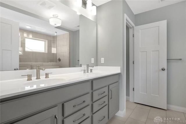 bathroom featuring baseboards, walk in shower, a sink, and tile patterned flooring