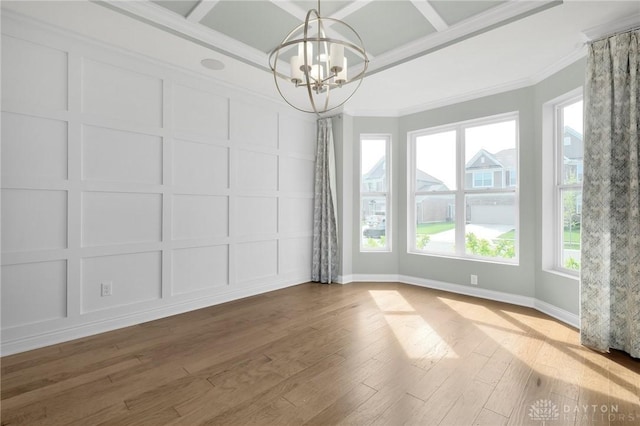 unfurnished dining area featuring ornamental molding, a decorative wall, and wood finished floors