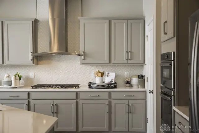 kitchen with gray cabinets, wall chimney exhaust hood, and gas stovetop