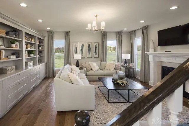 living area with recessed lighting, dark wood-style flooring, a notable chandelier, and a tile fireplace