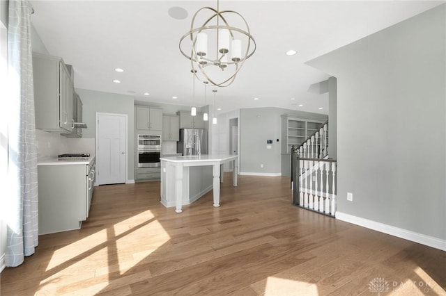 kitchen featuring light countertops, gray cabinets, stainless steel appliances, and a chandelier