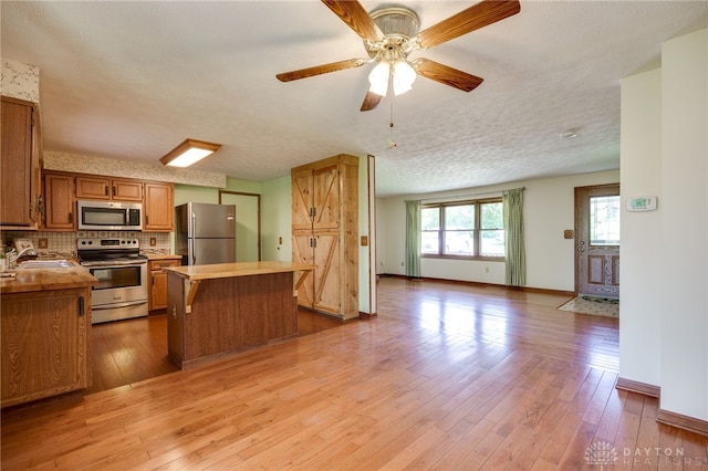 6139 N State Route 48, Clearcreek Twp, OH 45036 - kitchen featuring appliances with stainless steel finishes, open floor plan, light wood-type flooring, a center island, and tasteful backsplash