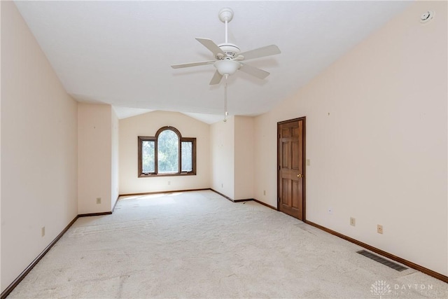 carpeted spare room with vaulted ceiling, a ceiling fan, visible vents, and baseboards