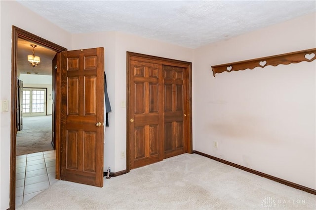 unfurnished bedroom with carpet floors, a textured ceiling, and baseboards