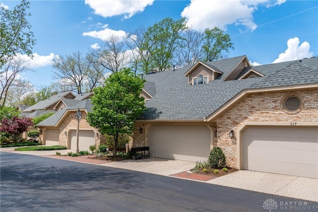 view of front of property featuring brick siding, a shingled roof, and a garage