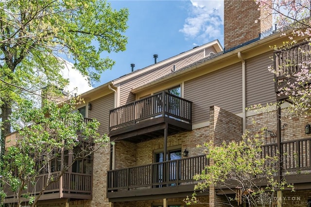 rear view of house with brick siding and a balcony