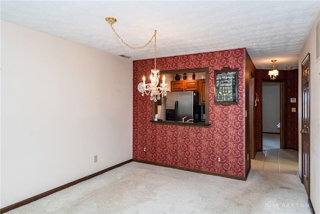 unfurnished dining area with wallpapered walls, baseboards, light colored carpet, and an inviting chandelier