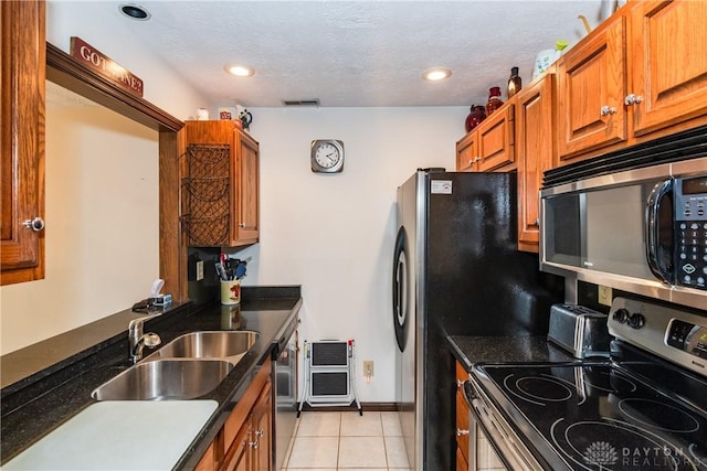 kitchen featuring stainless steel appliances, visible vents, a sink, light tile patterned flooring, and brown cabinetry