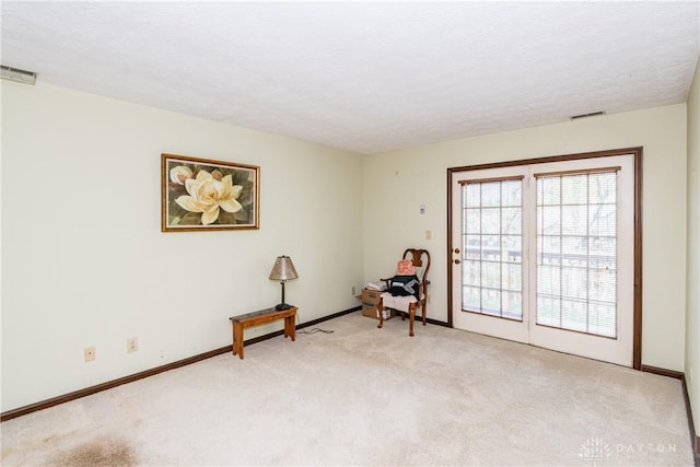 sitting room with light carpet, a textured ceiling, visible vents, and baseboards