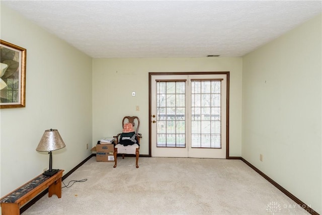 sitting room with light colored carpet, baseboards, a textured ceiling, and visible vents