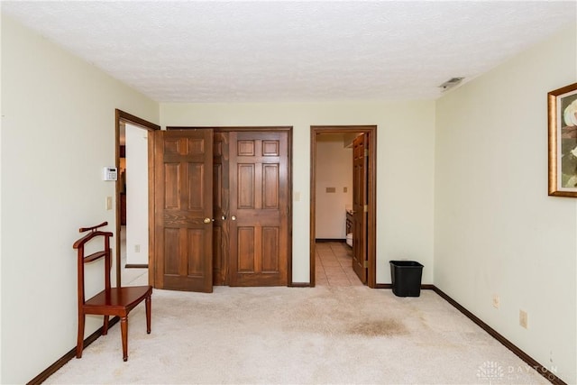 bedroom with light carpet, a textured ceiling, visible vents, and baseboards