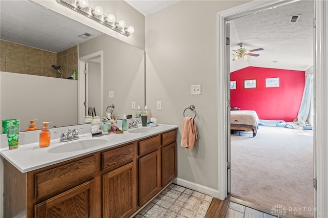 ensuite bathroom with a sink, double vanity, lofted ceiling, ceiling fan, and ensuite bath