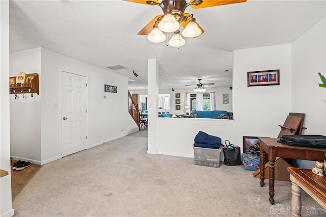 carpeted living area with baseboards, a ceiling fan, visible vents, and stairs
