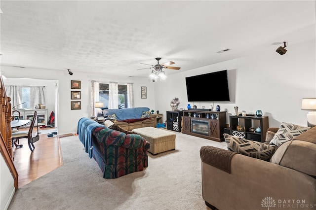 living area featuring a glass covered fireplace, a wealth of natural light, light colored carpet, and ceiling fan