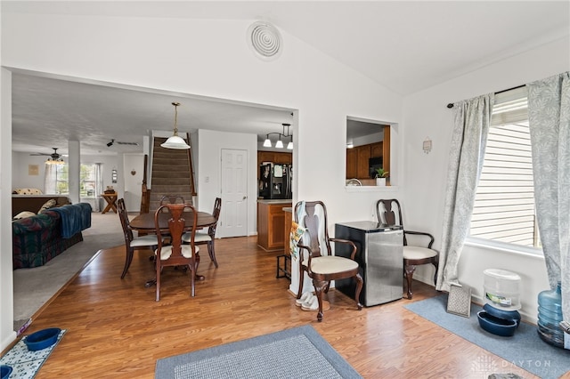 dining room featuring stairway, lofted ceiling, light wood finished floors, visible vents, and ceiling fan