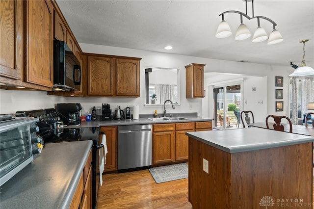 kitchen featuring a toaster, a sink, light wood-type flooring, black appliances, and hanging light fixtures
