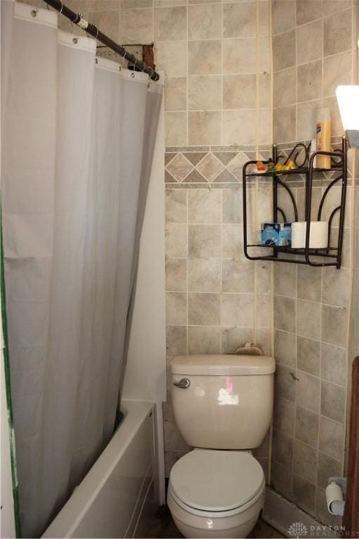 full bathroom with tile walls, shower / tub combo, and toilet