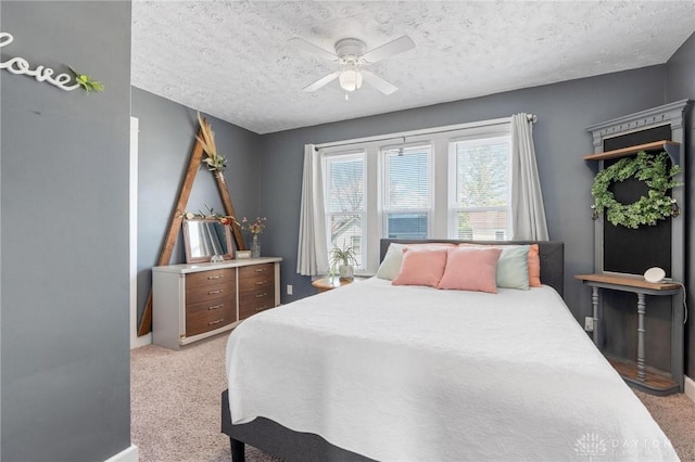 bedroom featuring baseboards, light carpet, a textured ceiling, and ceiling fan