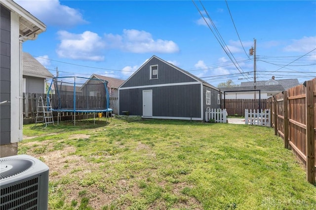 view of yard featuring central AC, a trampoline, a fenced backyard, and an outdoor structure