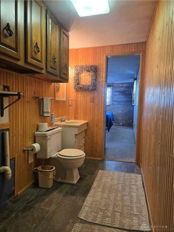 half bathroom featuring wood walls and toilet