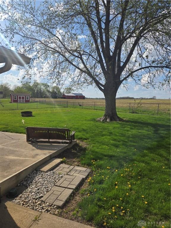 view of community with a lawn, a rural view, and fence
