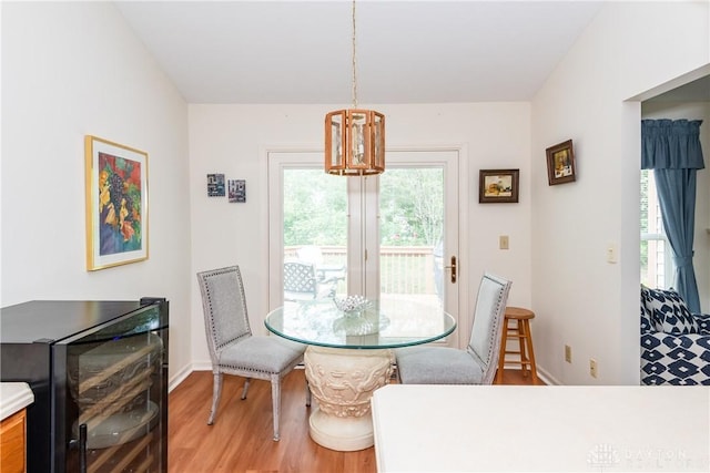 dining area with a notable chandelier, baseboards, light wood-style flooring, and beverage cooler