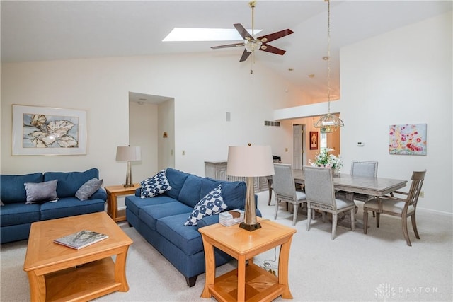 living room with high vaulted ceiling, a ceiling fan, visible vents, a skylight, and light colored carpet