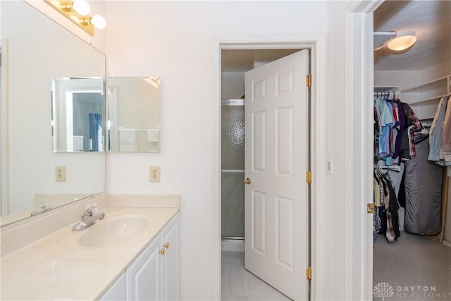 bathroom with vanity, a spacious closet, and a stall shower