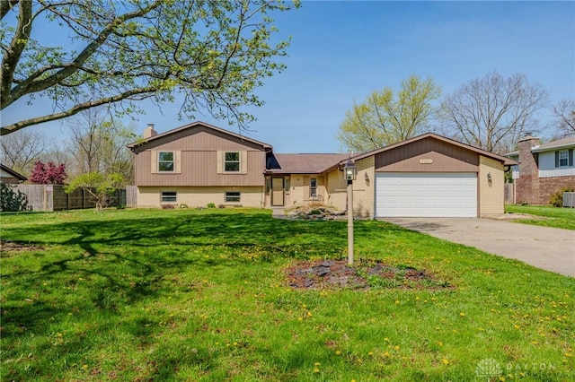 split level home featuring concrete driveway, a chimney, an attached garage, fence, and a front lawn