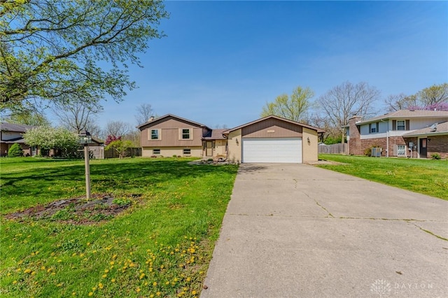 tri-level home featuring a front lawn, an attached garage, concrete driveway, and fence