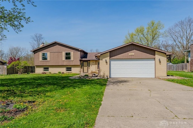 tri-level home featuring fence, a front yard, driveway, and an attached garage