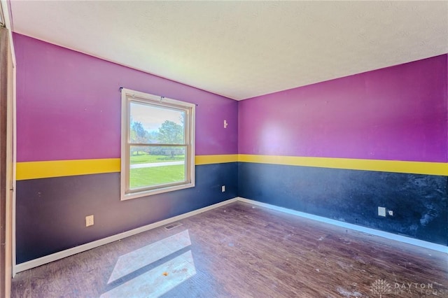 empty room with visible vents, wood finished floors, and baseboards