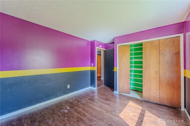 unfurnished bedroom with a closet, wood finished floors, and baseboards