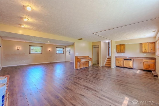 unfurnished living room with baseboards, stairs, a textured ceiling, and dark wood-style floors