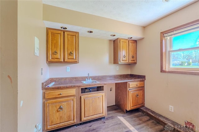 kitchen with a textured ceiling, brown cabinetry, dark wood-style floors, and a sink