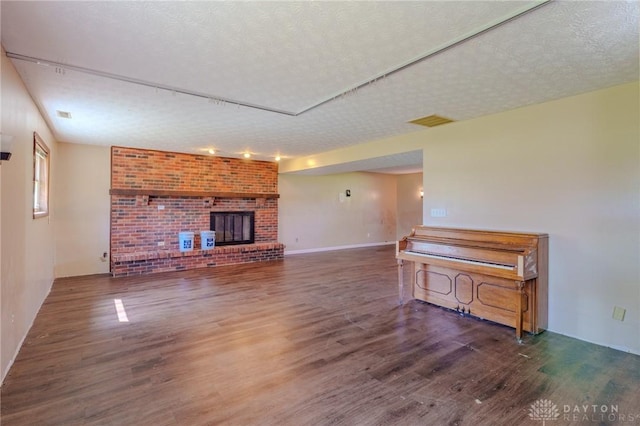 living room with a textured ceiling, visible vents, wood finished floors, and a fireplace