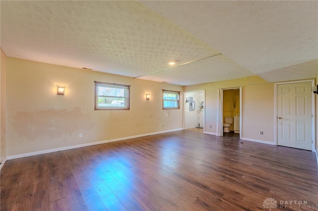 interior space with a textured ceiling, baseboards, and dark wood finished floors