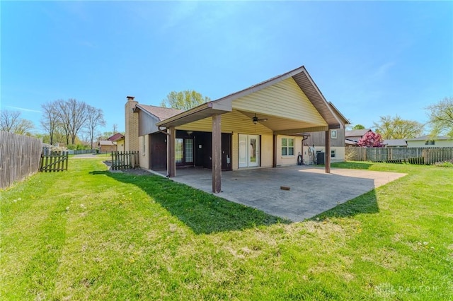 rear view of house featuring a chimney, a fenced backyard, ceiling fan, a patio area, and a lawn