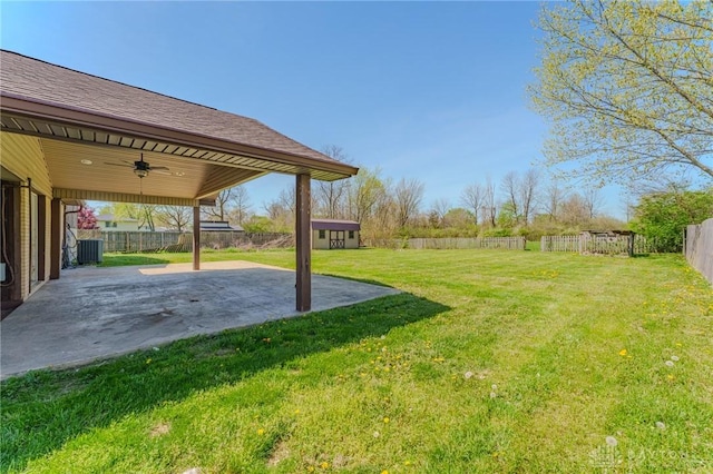 view of yard with central AC unit, an outdoor structure, a patio area, a fenced backyard, and a ceiling fan