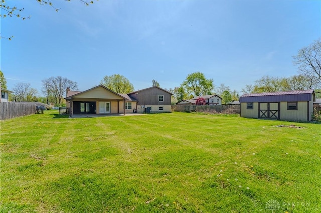 view of yard with an outdoor structure, a patio area, a shed, and a fenced backyard