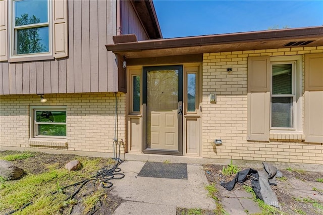 property entrance with board and batten siding and brick siding