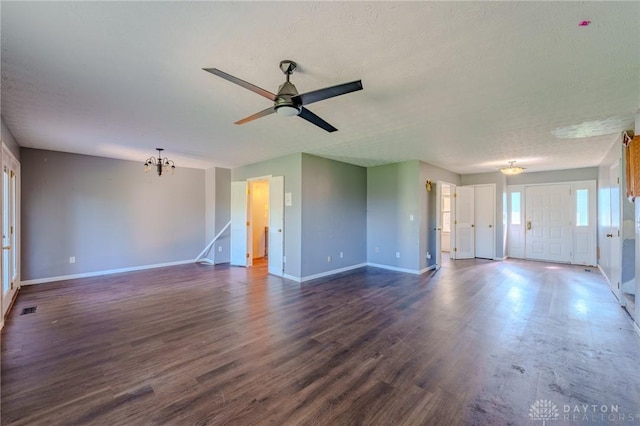 unfurnished living room featuring baseboards, visible vents, ceiling fan with notable chandelier, and dark wood-style floors