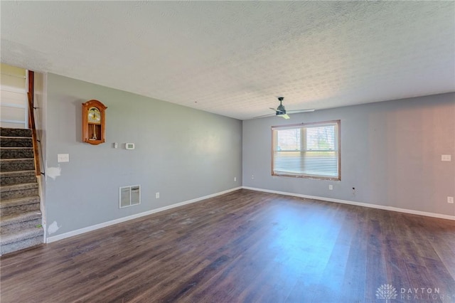 unfurnished room with stairway, dark wood-type flooring, a ceiling fan, visible vents, and baseboards