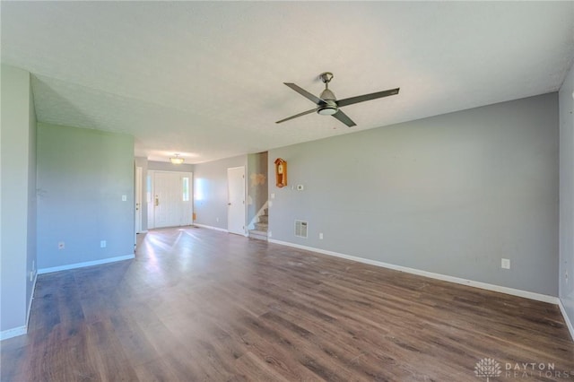 spare room featuring wood finished floors, ceiling fan, stairway, and baseboards