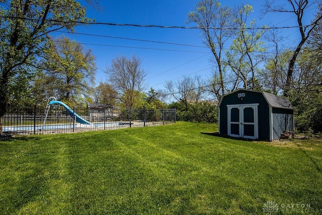view of yard with an outbuilding, a storage shed, a fenced in pool, and fence
