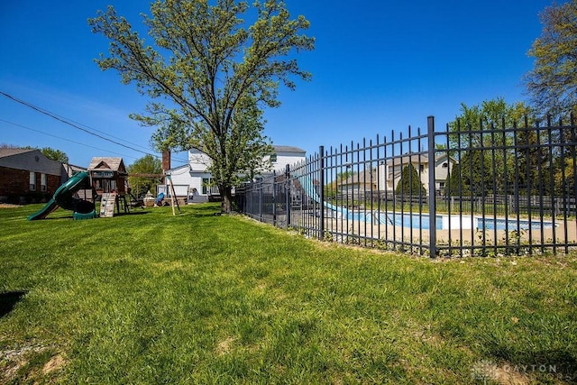view of yard with fence, playground community, and a fenced in pool