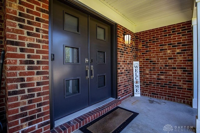 view of exterior entry with covered porch, french doors, and brick siding