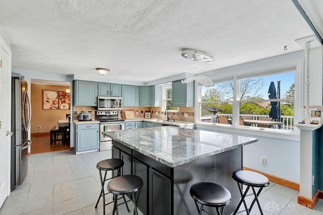 kitchen featuring appliances with stainless steel finishes, a kitchen bar, and baseboards