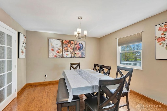 dining area with baseboards, an inviting chandelier, and light wood-style floors
